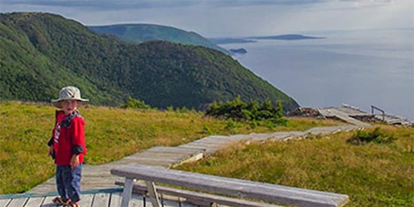 Kleinkind auf einem Wanderweg mit Aussicht aufs Meer in den Cape Breton Highlands